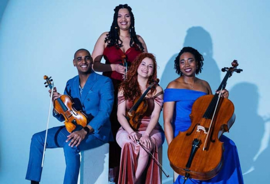 Photo of the four members of the Havana Quartet holding their string instruments.