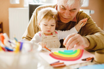 older man coloring a rainbow with a toddler