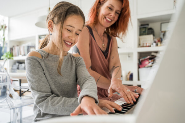 woman and younger girl playing piano together demonstrating suzuki music education